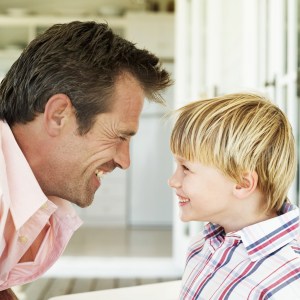 Young Man and a Young Boy (6-7) Looking at Each Other Laughing